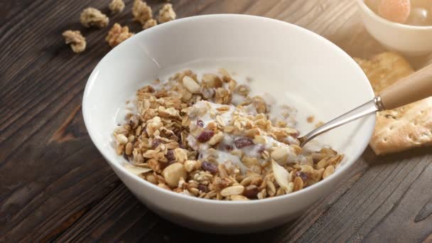 Homemade muesli cereals breakfast with white plain yogurt, dry nuts, in small bowl on rustic wooden background. Healthy granola, food clean eating, vegan diet, allergy-friendly weight loosing concept — Stock Video