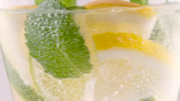 Closeup verfrissende frisdrank tonic bruisend sprankelend water, kalk in glas, ijsblokjes. Snijd citroen, minerale bubbels. Gezonde voeding. Koude limonade mojito cocktail twinkelende koolzuurhoudende frisdrank — Stockvideo
