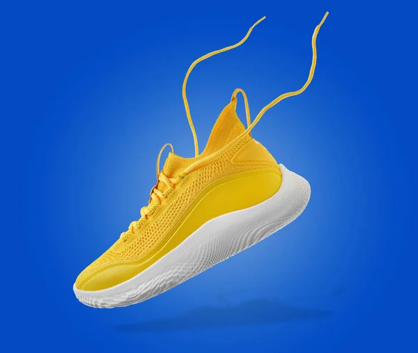 Flying yellow leather womens sneakers on blue background. Fashionable stylish sports casual shoes. Creative minimalistic layout with footwear. Mock up for design advertising for shoe store — Stock Photo, Image