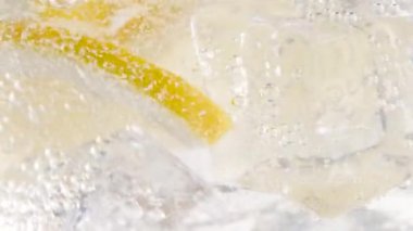 Makro ferahlatıcı soda tonik köpüklü su, camda limon, buz küpleri. Limon dilimi, mineral köpükleri. Sağlıklı, besleyici. Soğuk limonata mojito kokteyli. Karbonatlı meşrubat.