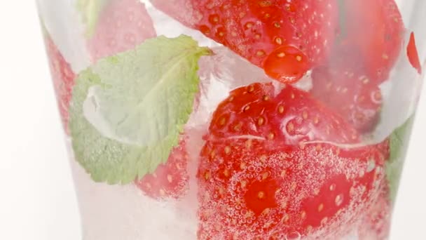 Koude verfrissende aardbeienlimonade of mojito cocktail met ijsblokjes en verse muntblaadjes. Berry plakjes in bruisende sprankelende tonic met bubbels, sap verfrissing koolzuurhoudende frisdrank of drank — Stockvideo