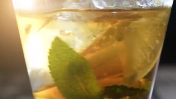 Detailní sklenice ledového čaje s kostkami ledu, plátky citronu, čerstvá máta. Zdravý osvěžující limonáda pro detoxikaci, sladké chutné nealkoholické nápoje nebo studené aromatické nápoje pro letní čas ve zpomaleném filmu — Stock video