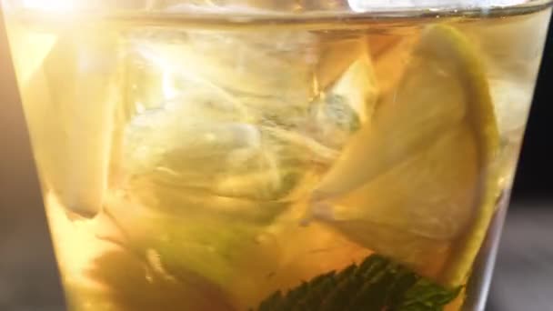 Крупним планом склянка крижаного чаю з кубиками льоду, нарізаним лимоном, свіжим перцем. Здоровий освіжаючий лимонад для детоксикації, солодкий смачний безалкогольний напій або холодний ароматний напій для літнього часу у повільному русі — стокове відео