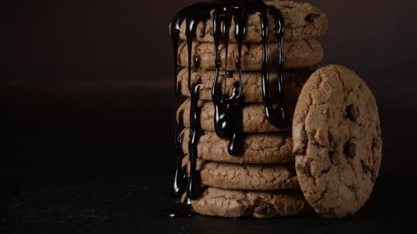 Verter extra oscuro derretido salsa de chocolate líquido sobre la pila de galletas caseras en cámara lenta. Galletas dulces, pastelería casera, textura líquida sobre fondo negro — Vídeo de stock