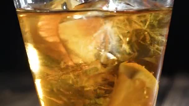 Eistee im Glas mit Eiswürfeln und Zitronenscheiben. Gesunde erfrischende Limonade zur Entgiftung, süße, schmackhafte Limonade oder kaltes aromatisches Getränk für den Sommer in Zeitlupe — Stockvideo