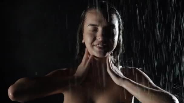 Attraente giovane ragazza millenaria in piedi sotto la doccia acqua corrente con spruzzi su tutto il corpo. Giovane donna bagnata sotto le gocce che cadono, in piedi sotto il flusso di acqua, bellezza e concetto di salute. — Video Stock