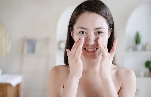 Joven multi étnica chica asiática tocando la cara con los dedos aplicar el cuidado de la piel utiliza crema hidratante. Rutina de la mañana, aseo, cuidado personal, cuidado de la piel tratamiento de belleza bodycare cosméticos concepto. — Foto de Stock