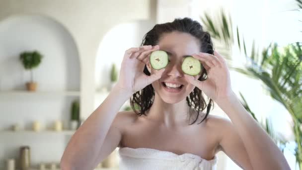 Funny mujer asiática cubriendo los ojos con pepinos fresco limpio sano cuidado de la piel concepto. Linda chica de raza mixta sosteniendo vegetales orgánicos durante la terapia de tratamiento de belleza disfrutar del cuidado corporal diario en el baño — Vídeo de stock