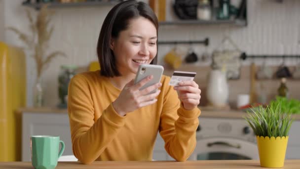 Mix Rennen weibliche Kundin mit Kreditkarte und Smartphone in den Verifizierungsprozess in mobilen Anwendungen beteiligt. Asiatische glückliche junge Frau beim Online-Bezahlen oder Einkaufen im Internet-Shop — Stockvideo