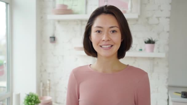 Glad ung vuxen asiatisk kvinna tittar på kameran, attraktiv tusenårig etnisk dam med vita tänder söt ansikte poserar för närbild porträtt hemma. — Stockvideo