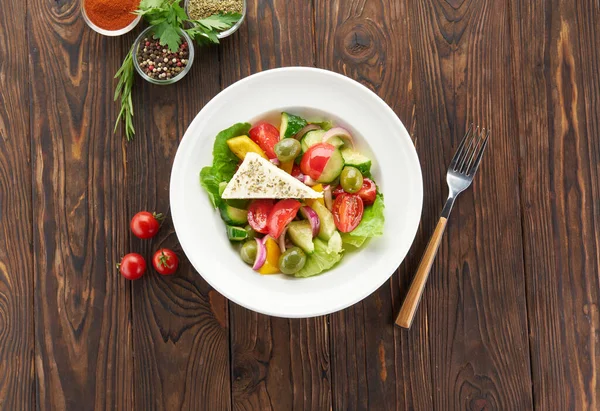Čerstvý řecký salát se sýrem Feta, rajčaty, okurkou, pepřem, olivami, červenou cibulí a salátem na dřevěném stole, výhled shora. Zdravé jídlo, vegetariánská strava, vaření doma — Stock fotografie