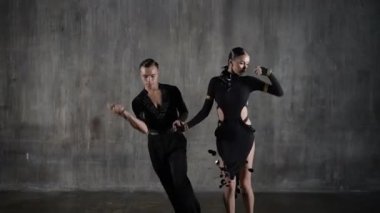 Milenyum danslarında dans eden siyah elbiseli genç çift stüdyo arka planında şehvetli bir şekilde dans ediyor. Latin dansı yapan profesyonel dansçılar. Hobi dans konsepti. İnsani duygular, aşk tutkusu