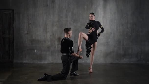 Jovem e elegante casal de salão de baile de dança milenar em vestido preto dançando em pose sensual sobre fundo grunge. Dançarinos profissionais dançando latino. Conceito de dança Hobby. Emoções humanas, amor e paixão — Vídeo de Stock