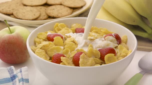 Cornflakes with strawberries and pouring milk — Stock Video