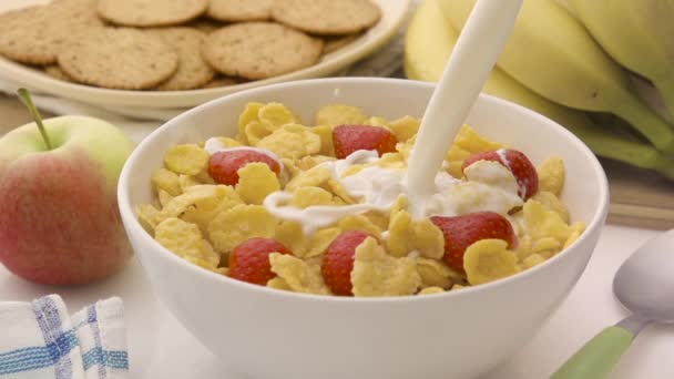 Verter leche con copos de maíz en un tazón blanco — Vídeo de stock