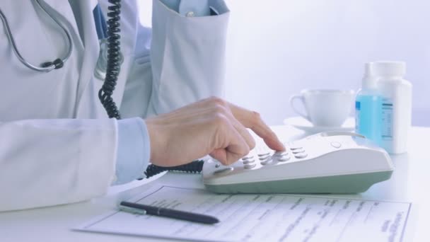 Чоловік лікар набирає телефон у медичному кабінеті — стокове відео