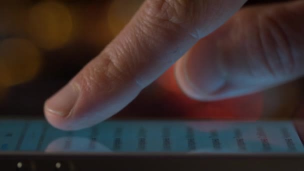 Мужской палец прокручивает изображения на сенсорном экране в темноте крупным планом — стоковое видео