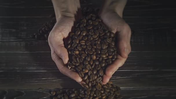 Grains de café torréfiés coulant des mains coupées — Video