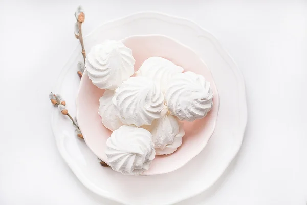 Marshmallows su piatto rosa gentile su uno sfondo bianco con ramoscello micio-salice. Sfondo pasquale . — Foto Stock