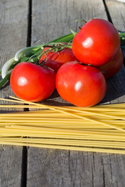 La pasta y los tomates sobre la rama a la mesa de madera . —  Fotos de Stock