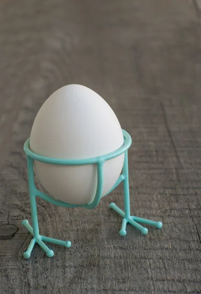 Wit van ei in blauwe grappige stand met poten op een houten achtergrond — Stockfoto