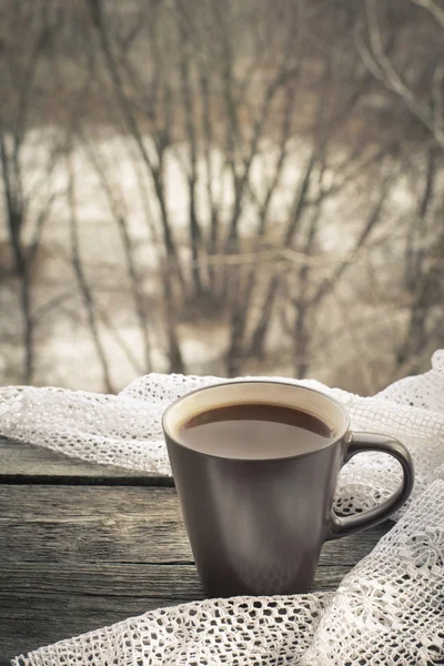 Чашка черного кофе с молоком перед окном и кружевами на деревянном фоне . — стоковое фото