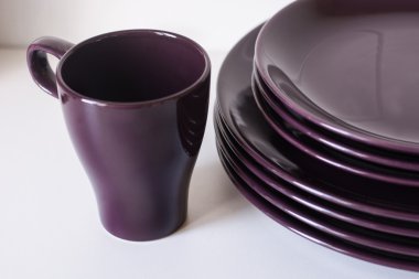 Mor teacups ve beyaz zemin üzerine plakalar