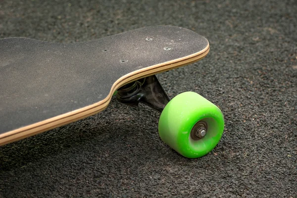 Old used skateboard isolated on the ground. Old style longboard. Black skateboard on an empty asphalt road. Shallow depth of field. — Stock Photo, Image