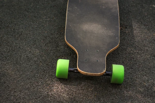 Old used skateboard isolated on the ground. Old style longboard. Black skateboard on an empty asphalt road. Shallow depth of field. — Stock Photo, Image