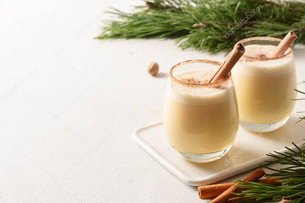 Two Christmas eggnogs with grated cinnamon and nutmeg on white background. Copy space.