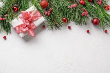 Kırmızı hediyeli Noel afişi, beyaz arkaplanlı köknar dalları ve fotokopi alanı. Tebrik kartı. Mutlu Noeller. Yukarıdan görüntüle.