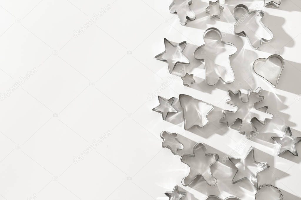 Border of Christmas-themed cookie cutters with shadow. Festive Xmas greeting card. Top view and flat lay. Space for text or design.