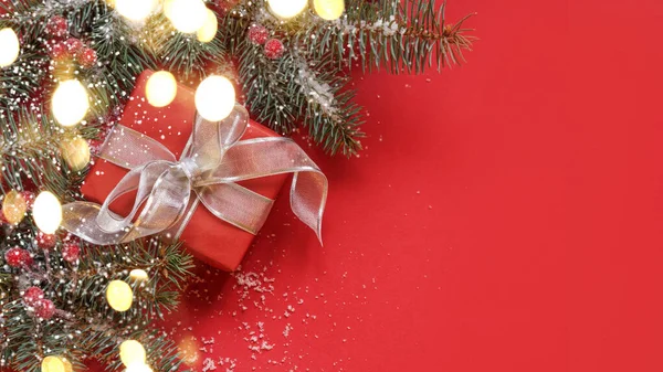 クリスマスの贈り物 ガーランド 赤い背景の常緑の枝 コピースペース付きクリスマスグリーティングカード — ストック写真
