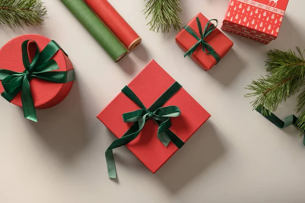 赤と緑のギフトボックス グレーの紙ロールでクリスマスの背景 休日のための準備と包装ギフト コピースペース付きのトップビュー — ストック写真