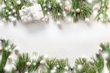Beyaz hediyeli karlı bir Noel çerçevesi, gümüş takılar, beyaz arka planda her zaman yeşil dallar. Kopya alanı olan Xmas tebrik kartı. Üst Manzara. Mutlu yıllar..