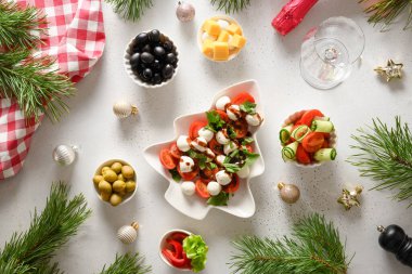 Caprese salatasıyla Noel yemeği ve beyaz masadaki Noel partisi için çeşitli sebze yemekleri. Yukarıdan görüntüle.