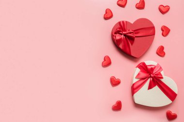 Kırmızı kutular ve pembe ışık arka planında kalpler olan Sevgililer Günü konsepti. Düz yatıyordu. Kopyalama alanı olan tebrik kartı.