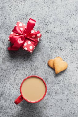 Kahve fincanı ve hediye, gri masada ev yapımı kalp kurabiyeleri. Sevgililer Günü tebrik kartı. Üst Manzara. Dikey biçim.