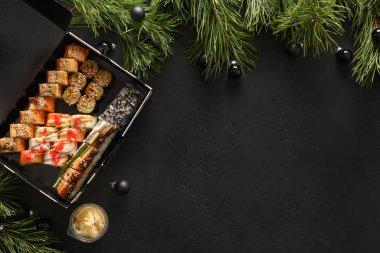 Suşi seti ve bayram siyah süslemesi olan şenlikli Noel Asya yemekleri..
