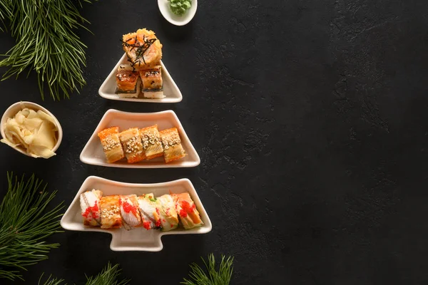 Sushi zestaw w talerzu jako choinka ozdobione gałązki jodły na czarno. — Zdjęcie stockowe