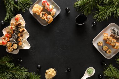 Noel yemeği, suşi seti ve siyah üzerine Noel süslemesi..