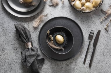 Altın yumurta ve siyah dekorlu Paskalya sofrası. Üst Manzara. Mutlu bayramlar. Yemek servisi..