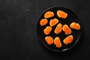 Siyah arka planda parti için Red Somon Havyarı kanepesi. Bayram yemeği. Lezzetli aperatif ve şampanya. Boşluğu kopyala.