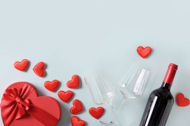 Sevgililer Günü hediyesi, kalpler ve kırmızı şarap mavi üzerine.