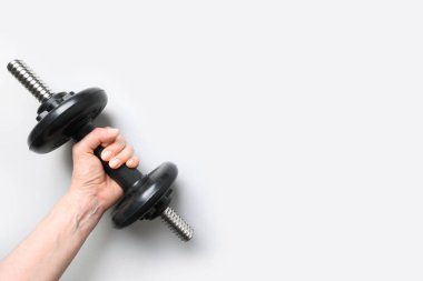 Gri arka planda siyah halterli bir kadın. Spor fitness ekipmanları.