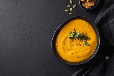 Sonbahar balkabağı çorbası garnitür mikro yeşillikler ve siyah arka planda malzemeler.