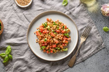 Gri masadaki sebzelerle hecelenmiş tahıl gevreği salatası. Yukarıdan görüntüle.