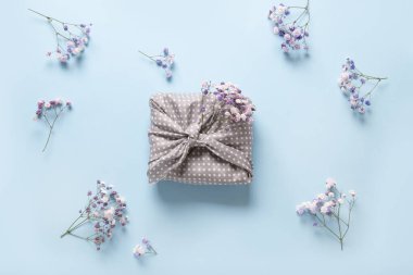 Bahar çevre dostu hediye. Gri tekstil ve mavi üzerine çiçekler. Sıfır kayıp. Geleneksel Japon Furoshiki tarzı.