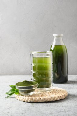 Klorella sağlıklı bir içecek, gri bir arka planda camla..