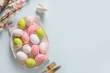 Paskalya pastel yumurtaları ve bahar çiçekleri mavi üzerine çiçek açıyor..